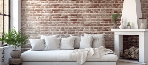A white living room with a plush couch and a fireplace. The room features a daybed with cushions in a corner and a white brick wall. Large windows let in natural light.