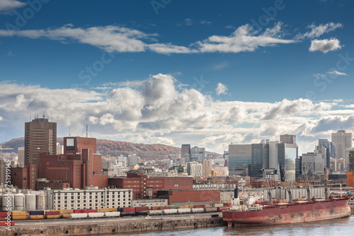 Panorama of Montreal with a cargo ship in the industrial port of Montreal, Quebec, with the skyline and center business district with their high rise skyscrapers behind. © Jerome