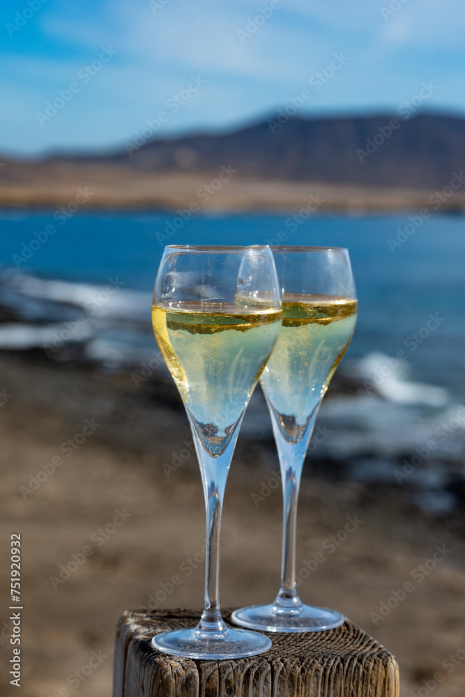 Pouring a glass of champagne on vacation, south of Fuerteventura, Canary islands, blue ocean, mountains Pouring a glass of champagne on vacation, south of Fuerteventura, Canary islands, blue ocean, mountains