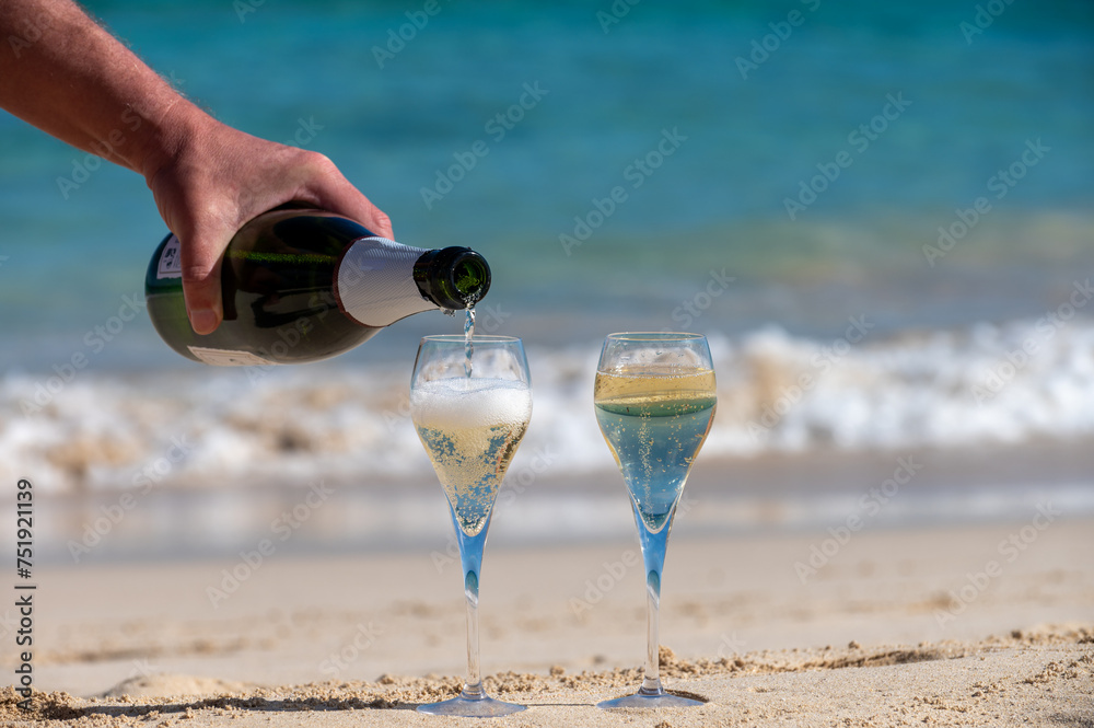 Obraz premium Pouring a glass of champagne on vacation, south of Fuerteventura, Canary islands, blue ocean, mountains