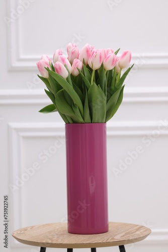 Beautiful bouquet of fresh pink tulips on table near white wall