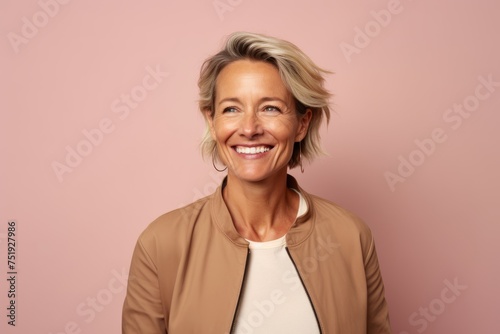 Portrait of smiling middle aged woman looking at camera isolated on pink background
