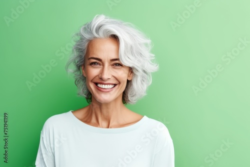 Portrait of a happy senior woman smiling at the camera over green background