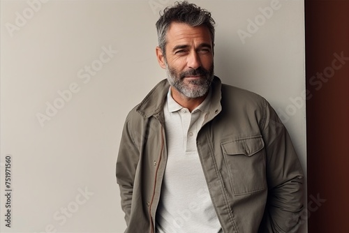Portrait of a handsome mature man with grey hair and beard wearing a green jacket