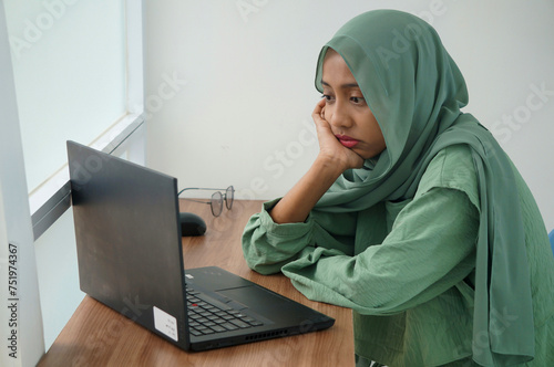 A muslim woman working at home using laptop