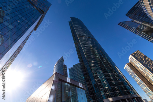 Skyscrapers cover the blue sky in the city center. The bright sun in the sky.