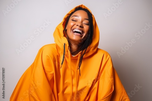 Young african american woman wearing a yellow raincoat and laughing © Iigo