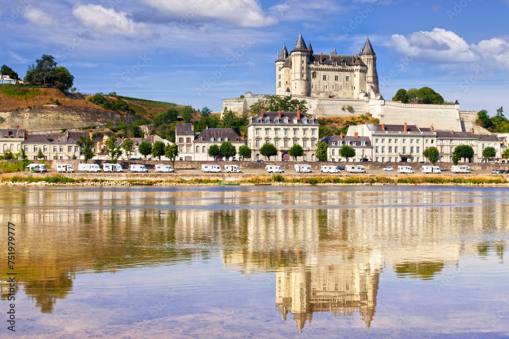 Saumur on the banks of the Loire River, Loire Valley, France. A long row of camper vans can be seen parked beside the river. - obrazy, fototapety, plakaty 