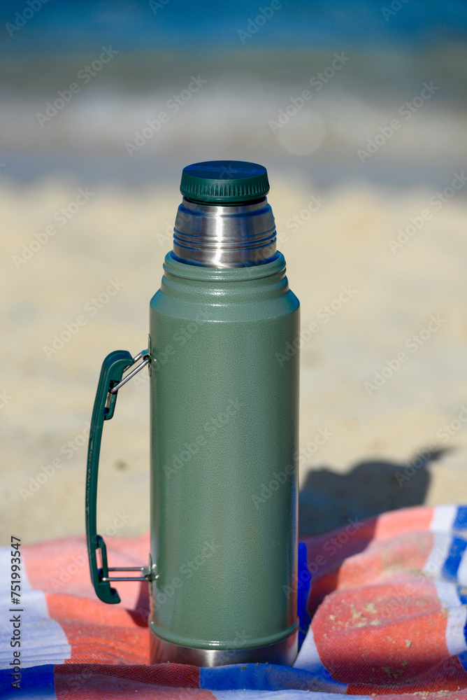 Authentic green Stanley Thermos on the beach in summer
