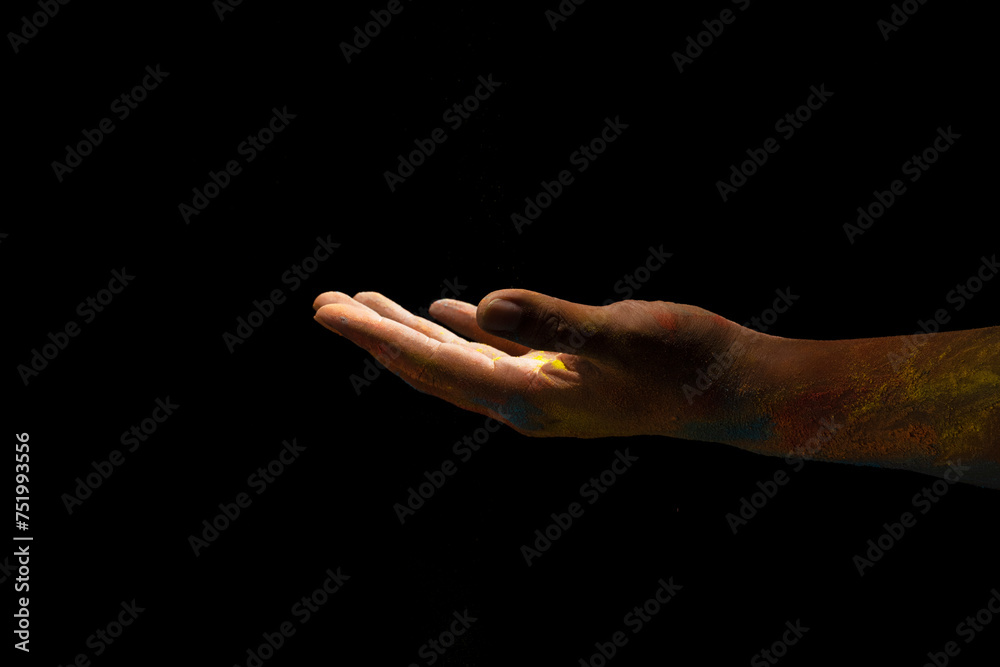 Close up hand covered with holi powder isolated over black background. Holi festival concept.