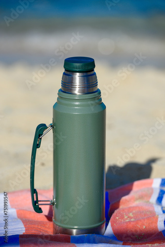 Obraz na płótnie Authentic green Stanley Thermos on the beach in summer w salonie