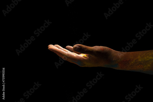 Close up hand covered with holi powder isolated over black background. Holi festival concept.