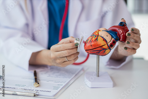 Heart Disease Dr. Ying provides advice on heart disease treatment. A cardiologist while giving a consultation shows an anatomical model of a human heart to an elderly patient talking about heart disea photo