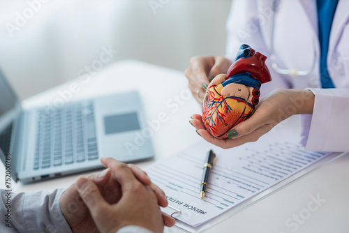 Heart Disease Dr. Ying provides advice on heart disease treatment. A cardiologist while giving a consultation shows an anatomical model of a human heart to an elderly patient talking about heart disea photo