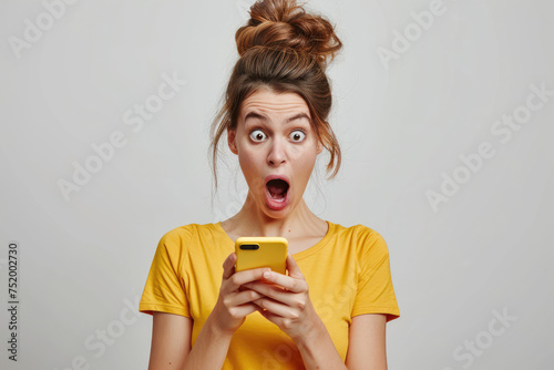 a woman looks at mobile phone with surprised open mouthed expression  © Kien