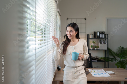 Free Download Confident Asian businesswoman working on real estate projects Online financial business, accounting, and drinking coffee while working, sitting happily in the office at home. - GFXLoad
