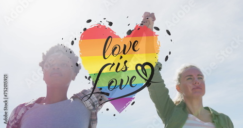 Image of rainbow heart and love is love over lesbian couple holding hands outdoors