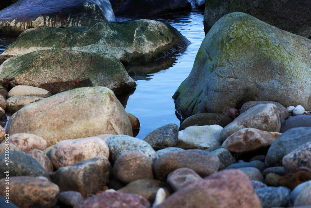 The clear water of an Alpine stream among the rocks in the mountains during the day. The clear water of an Alpine stream among the rocks in the mountains during the day.