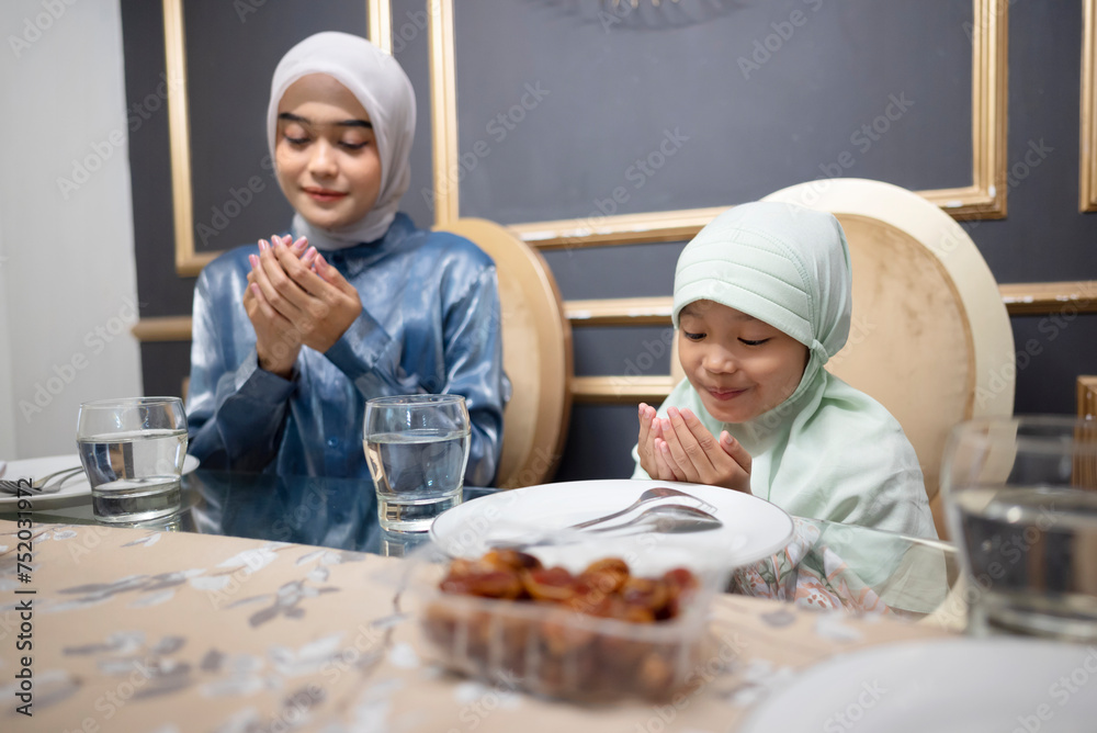 Indonesian muslim family praying together for breakfasting with meals on the dining table during ramadan. Indonesian muslim family praying together for breakfasting with meals on the dining table during ramadan.
