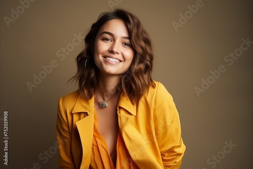 Portrait of beautiful smiling young woman in yellow jacket. Studio shot. © Iigo