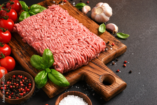 Minced pork and beef on a wooden board. Minced meat with spices on a dark background