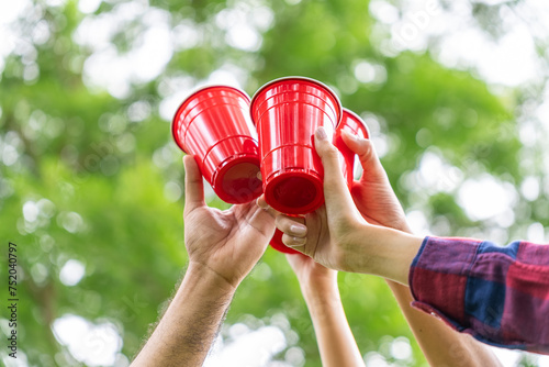 Close up hands of diverse group friends clinking a beer cup together. They feeling relaxed and refreshing while camping in the nature. Recreation and journey outdoor activity lifestyle.