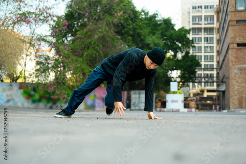Shot of young male hip hop dancer in stylish clothes in motion dances in city street