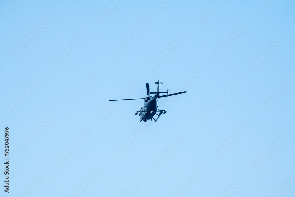 A helicopter is flying away on isolated blue sky A helicopter is flying away on isolated blue sky