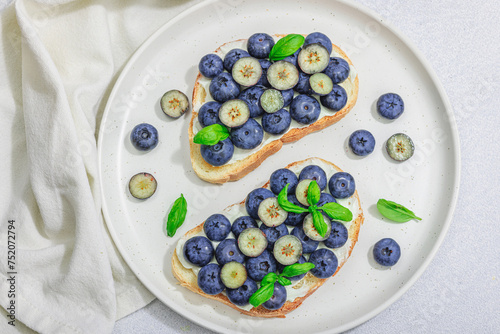 Fresh bread sandwiches with sweet blueberries, cream cheese and basil leaves. Good morning concept