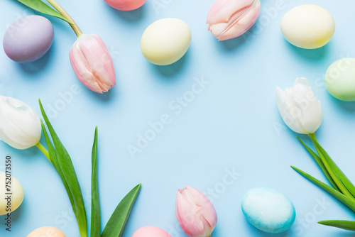 Happy Easter composition. Easter eggs on colored table with yellow Tulips. Natural dyed colorful eggs background top view with copy space © sosiukin