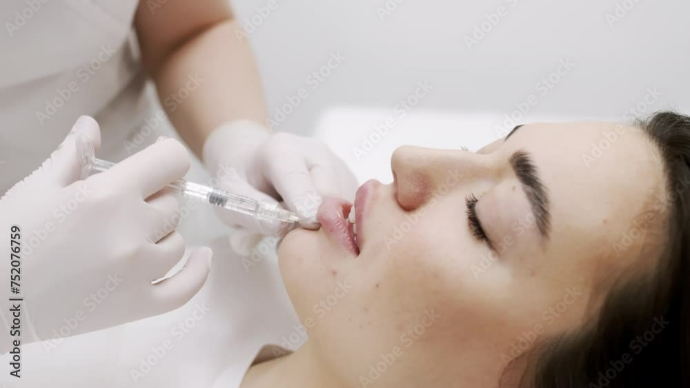 The procedure for lip augmentation and correction in a cosmetology salon. The specialist gives an injection to the patient's lips. Concept of cosmetology, cosmetic injections, and cosmetic surgery. The procedure for lip augmentation and correction in a cosmetology salon. The specialist gives an injection to the patient's lips. Concept of cosmetology, cosmetic injections, and cosmetic surgery.