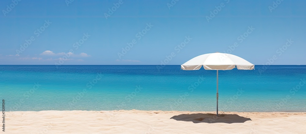 Tranquil Beach Scene with a White Umbrella Providing Serene Shade Against a Deep Blue Ocean