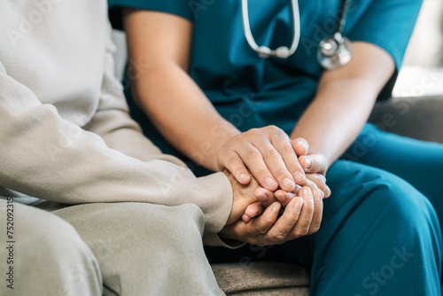 A female nurse caregiver holds hands to encourage and comfort an elderly woman. For care and trust in nursing homes for people of retirement age Caregiver helping elderly woman provides medical advice