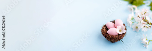 Stylish background with colorful easter eggs isolated on blue background with white blooming sakura branch. Flat lay, top view, mockup with copy space, overhead, template