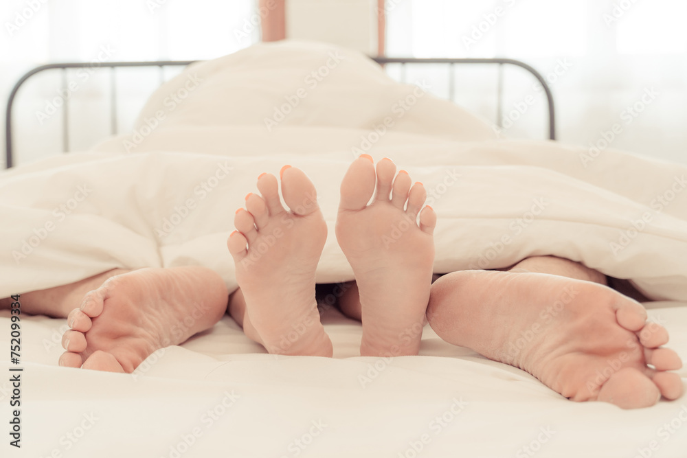 Rear view of a couple having sex in bed. Passionate love. Feet of a