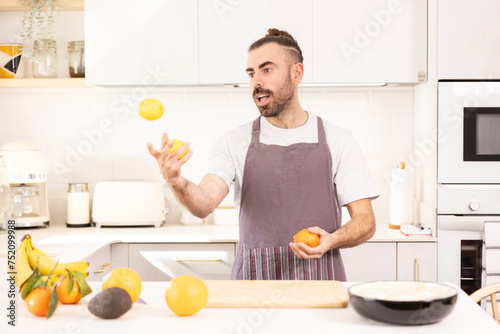 juggle, long-haired man cooking at home looking at tablet, chopping vegetables