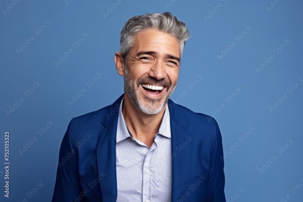 Portrait of handsome mature man laughing and looking at camera against blue background Portrait of handsome mature man laughing and looking at camera against blue background