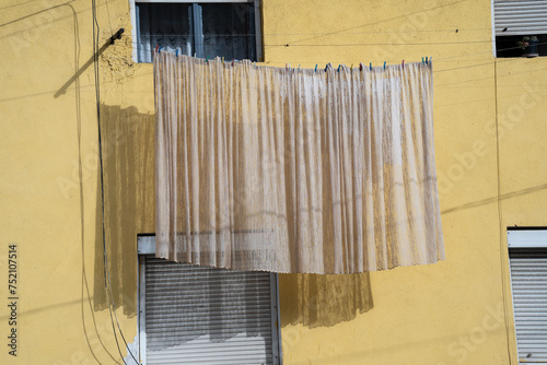 Yellow wall facade. Hanging curtain left for drying.