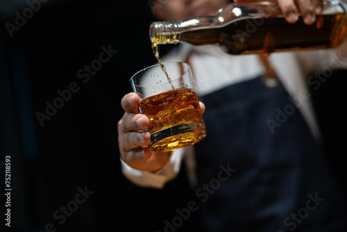 Bartender pours whiskey to customer in tavern