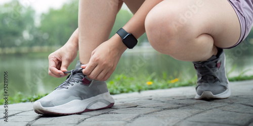 Woman tying shoe laces. Closeup of female sport fitness runner getting ready for jogging outdoors on park