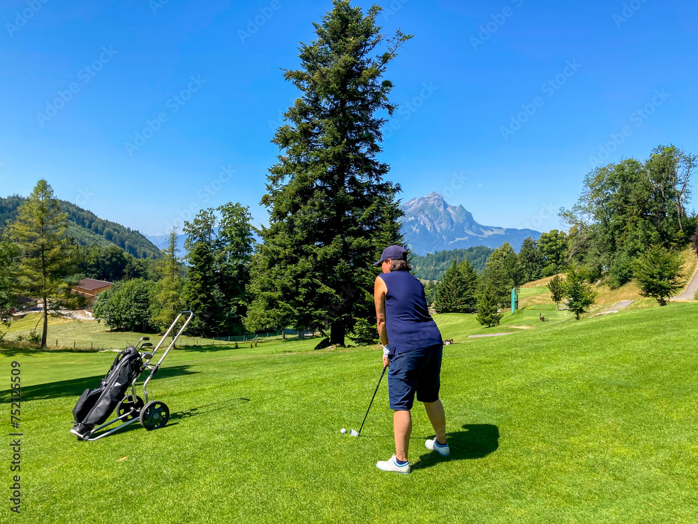 Golfer Teeing Off with Mountain Peak Pilatus View and the Moon in a Sunny Summer Day in Burgenstock, Nidwalden, Switzerland. Golfer Teeing Off with Mountain Peak Pilatus View and the Moon in a Sunny Summer Day in Burgenstock, Nidwalden, Switzerland.