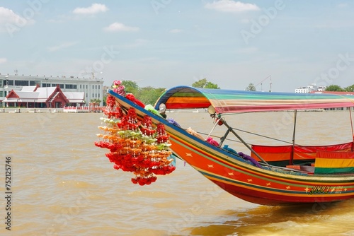 Photography A colourful Thai longtail boat with flower garlands docked on the banks of the C