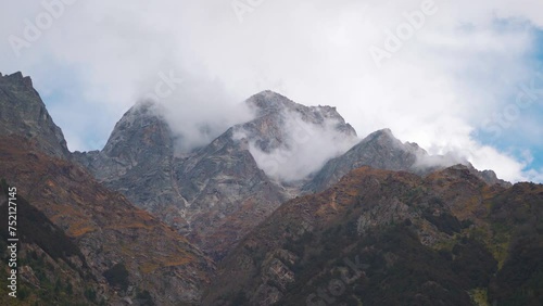 4K Time-lapse shot of dark stormy clouds above the Himalayan mountain peak at Sangla in Baspa Valley at Kinnaur, Himachal Pradesh, India. Clouds rolling above the mountain peaks during the day. photo