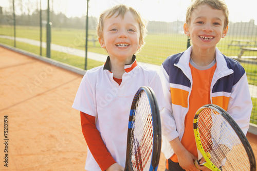 Two Young Boys Holding Tennis Rackets Smiling
