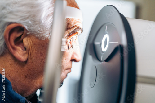 Elderly patient receives a glaucoma screening using a laser eye scanner. photo