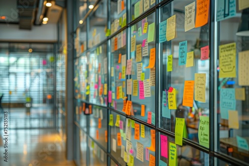 A glass wall covered with multi-colored sticky notes, symbolizing brainstorming and project planning in a modern office environment. photo