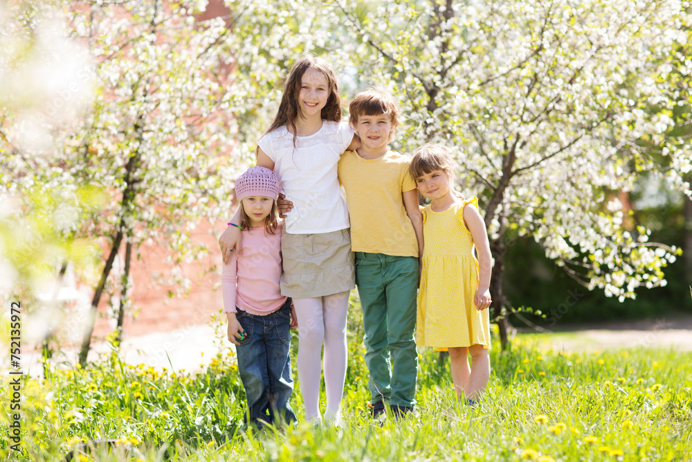 Fototapeta premium group kids friends spend time together in a flowering garden in spring.