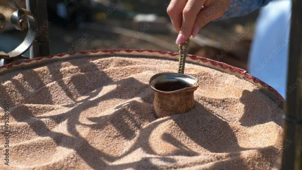 Street food with coffee on sand. A man hand try to preparing coffee life turkish one on the hot sand during day time.