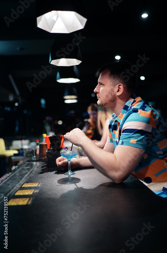 Happy smiling young man drinking cocktail in bar