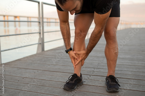 Runner guy having leg injury outside pressing shin in pain